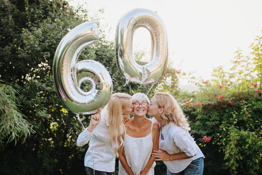 60 歲生日派對創意：女兒們拿著 60 號氣球親吻母親的臉頰