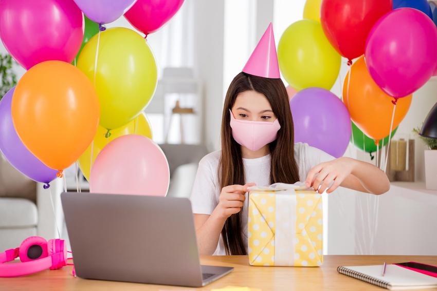 孩子們的隔離生日創意:女孩在筆記本電腦前打開禮盒