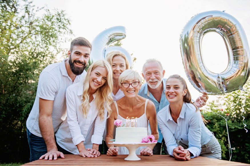 60 歲生日派對創意：女人在蛋糕後微笑，家人圍著